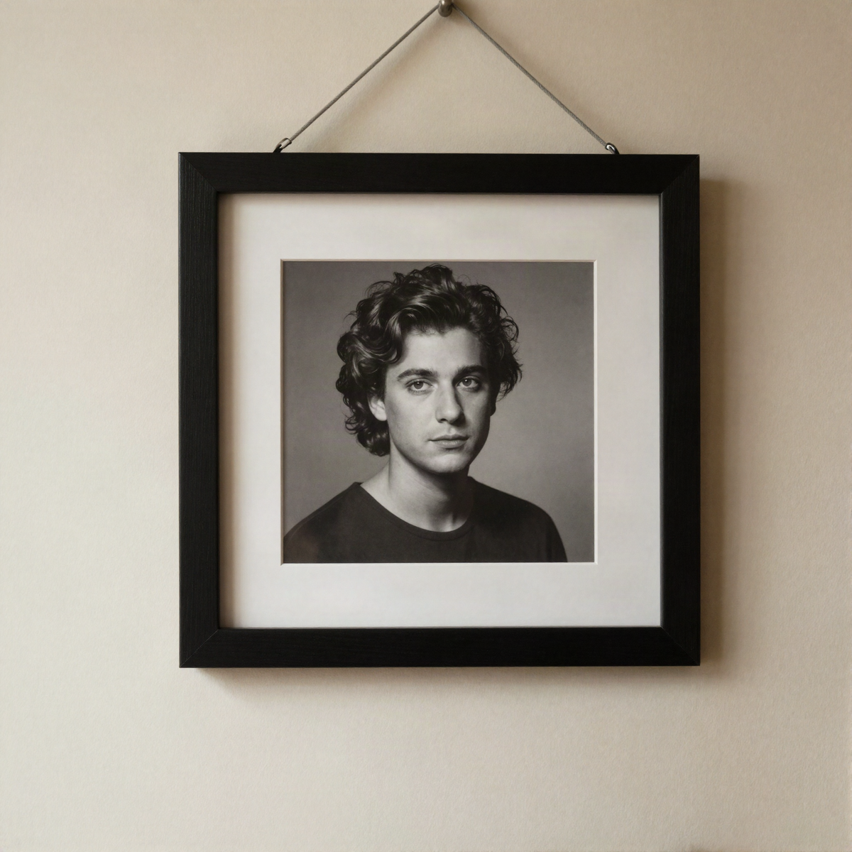 A black timber frame holding a black and white portrait on a warm plaster wall